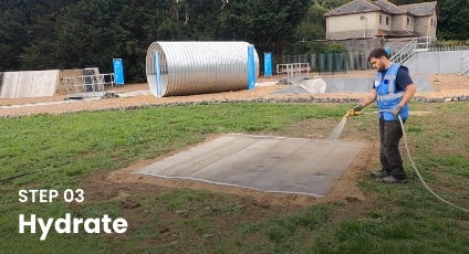 Worker spraying water over an Instaslab foundation mat during Step 03 of installation. Worker spraying water over an Instaslab foundation mat during Step 03 of installation.