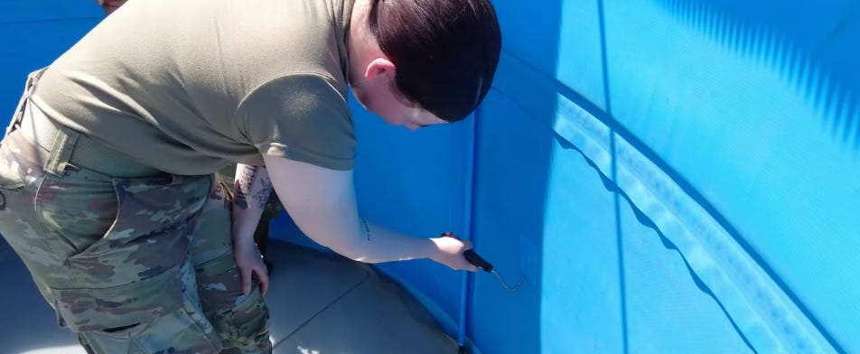 Technician inspecting the interior wall of a blue tank with a handheld tool during a tank repair or leak detection process. Technician inspecting the interior wall of a blue tank with a handheld tool during a tank repair or leak detection process.