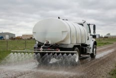 Water truck spraying liquid from a rear-mounted tank on a dirt road Water truck spraying liquid from a rear-mounted tank on a dirt road
