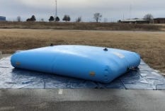 Collapsible water storage bladder placed on a protective ground tarp Collapsible water storage bladder placed on a protective ground tarp