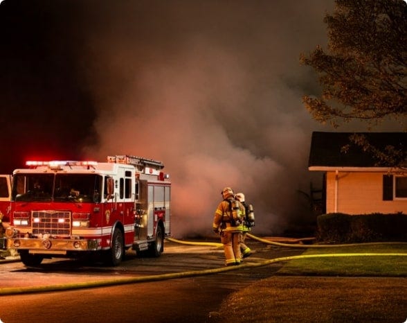 A fire truck outside a burning house with fire fighters ready to get into action. A fire truck outside a burning house with fire fighters ready to get into action.