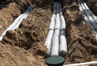 EZflow drainfield bundles installed in parallel trenches with a green septic access cover visible in the foreground. EZflow drainfield bundles installed in parallel trenches with a green septic access cover visible in the foreground.