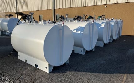 Row of white horizontal emergency fuel storage tanks with dispensing equipment lined up outside an industrial building. Row of white horizontal emergency fuel storage tanks with dispensing equipment lined up outside an industrial building.