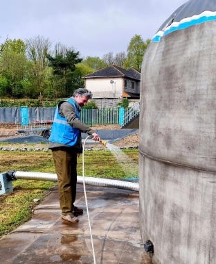 Man spraying water on a dome-shaped tank to cure and strengthen the concrete shell. Man spraying water on a dome-shaped tank to cure and strengthen the concrete shell.