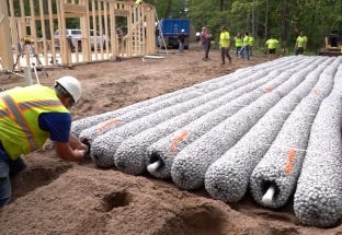 Workers installing rows of EZflow drainfield bundles at a residential construction site for long-term septic system performance. Workers installing rows of EZflow drainfield bundles at a residential construction site for long-term septic system performance.
