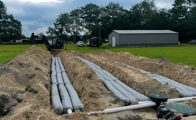 EZflow drainfield bundles installed in long parallel trenches beside a septic tank system on a residential property. EZflow drainfield bundles installed in long parallel trenches beside a septic tank system on a residential property.
