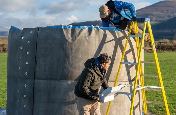 Workers inspecting and repairing the top edge of a concrete Omni Tank using a ladder in an open field. Workers inspecting and repairing the top edge of a concrete Omni Tank using a ladder in an open field.