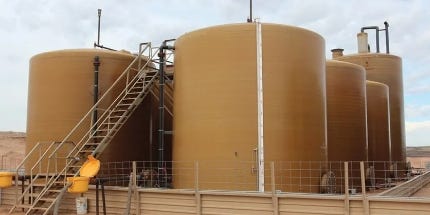 Large above-ground fiberglass storage tanks with access stairs and industrial piping at a utility or processing site. Large above-ground fiberglass storage tanks with access stairs and industrial piping at a utility or processing site.