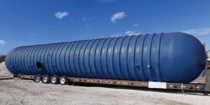 Large blue underground fiberglass storage tank loaded on a flatbed trailer for transport. Large blue underground fiberglass storage tank loaded on a flatbed trailer for transport.