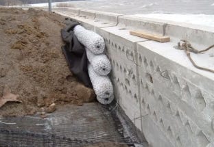 EZflow drainage bundles installed behind a concrete retaining wall to support subsurface water drainage. EZflow drainage bundles installed behind a concrete retaining wall to support subsurface water drainage.