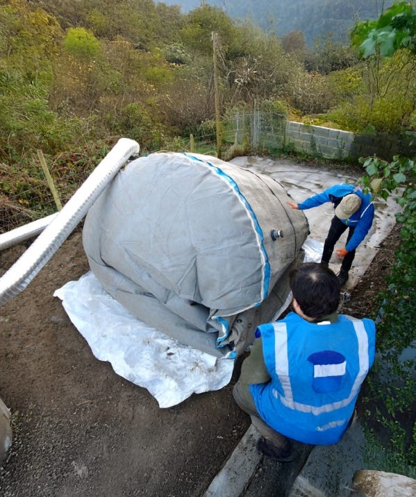 Workers installing a flexible water tank on a prepared ground base with piping attached. Workers installing a flexible water tank on a prepared ground base with piping attached.