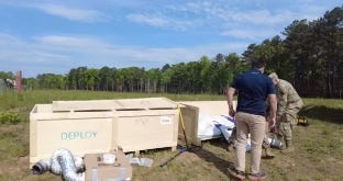 Workers unloading a compact packaged tank system from crates at an outdoor installation site. Workers unloading a compact packaged tank system from crates at an outdoor installation site.