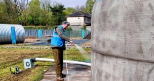 Man spraying water on a dome-shaped tank to cure and strengthen the concrete shell. Man spraying water on a dome-shaped tank to cure and strengthen the concrete shell.