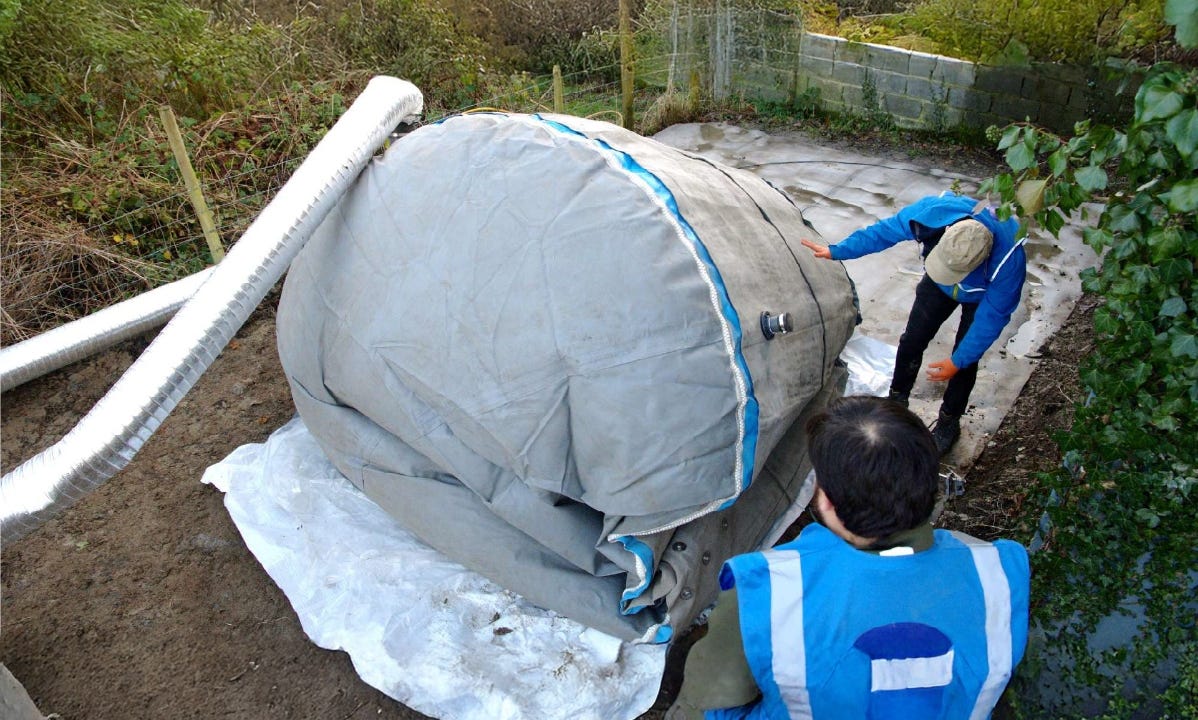Workers installing a flexible water tank on a prepared ground base with piping attached. Workers installing a flexible water tank on a prepared ground base with piping attached.