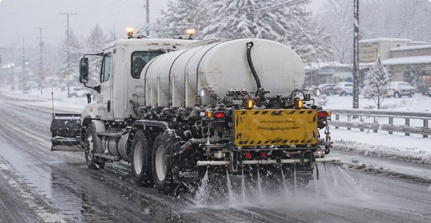 Snowplow truck spraying brine on a snowy road for winter ice and snow control. Snowplow truck spraying brine on a snowy road for winter ice and snow control.