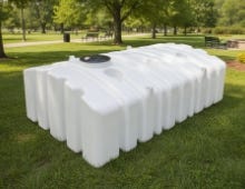 White multi-use underground tank placed on grass in a park-like outdoor setting with trees in the background. White multi-use underground tank placed on grass in a park-like outdoor setting with trees in the background.